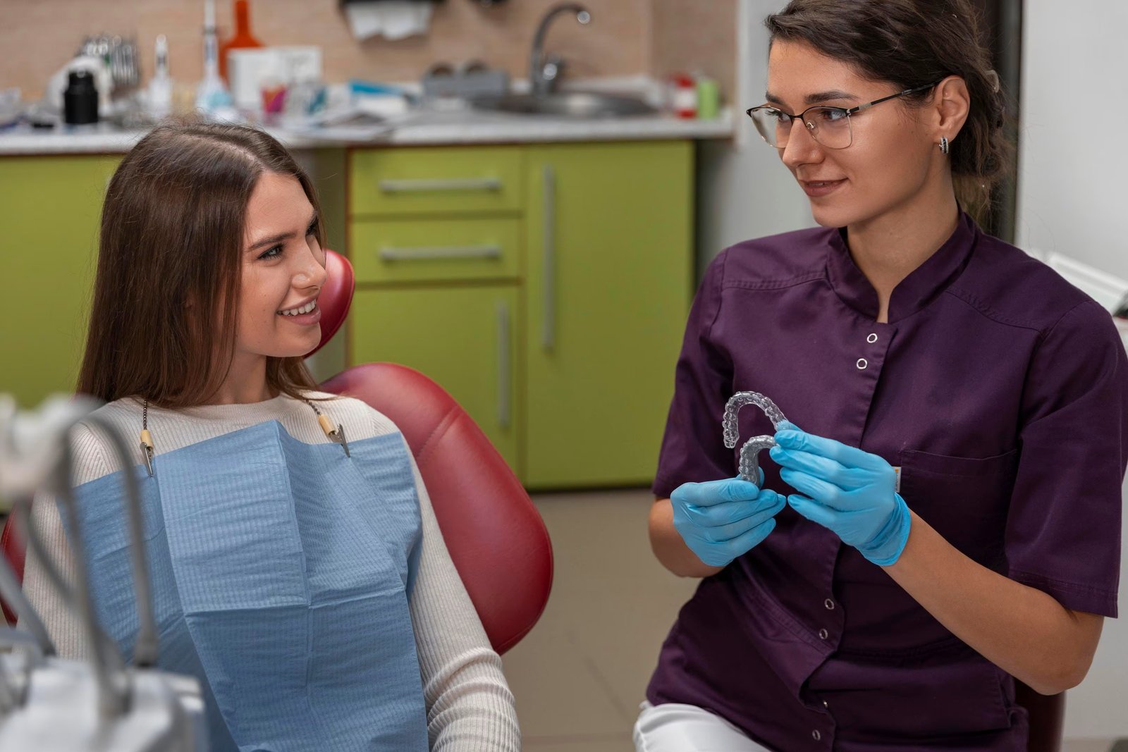 Orthodontic assistant showing an adult patient a clear Invisalign aligner