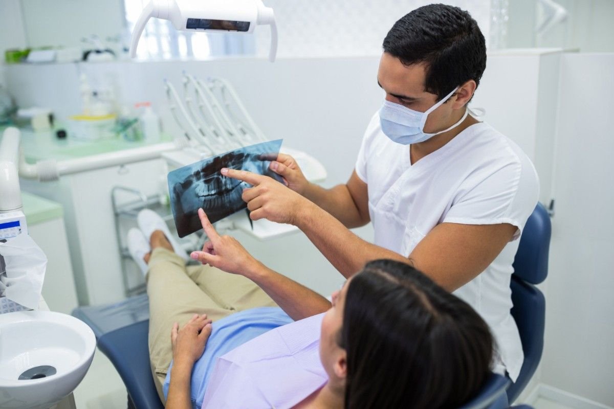 Orthodontist reviewing a jaw X-ray with a patient in the chair