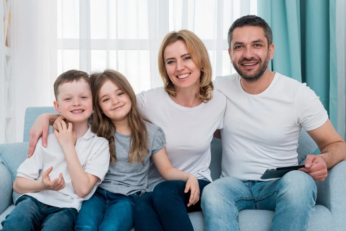 A family of four smiling together at home