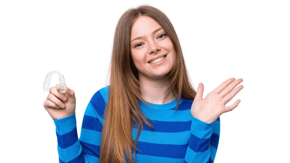 Smiling orthodontic patient holding a clear Invisalign aligner