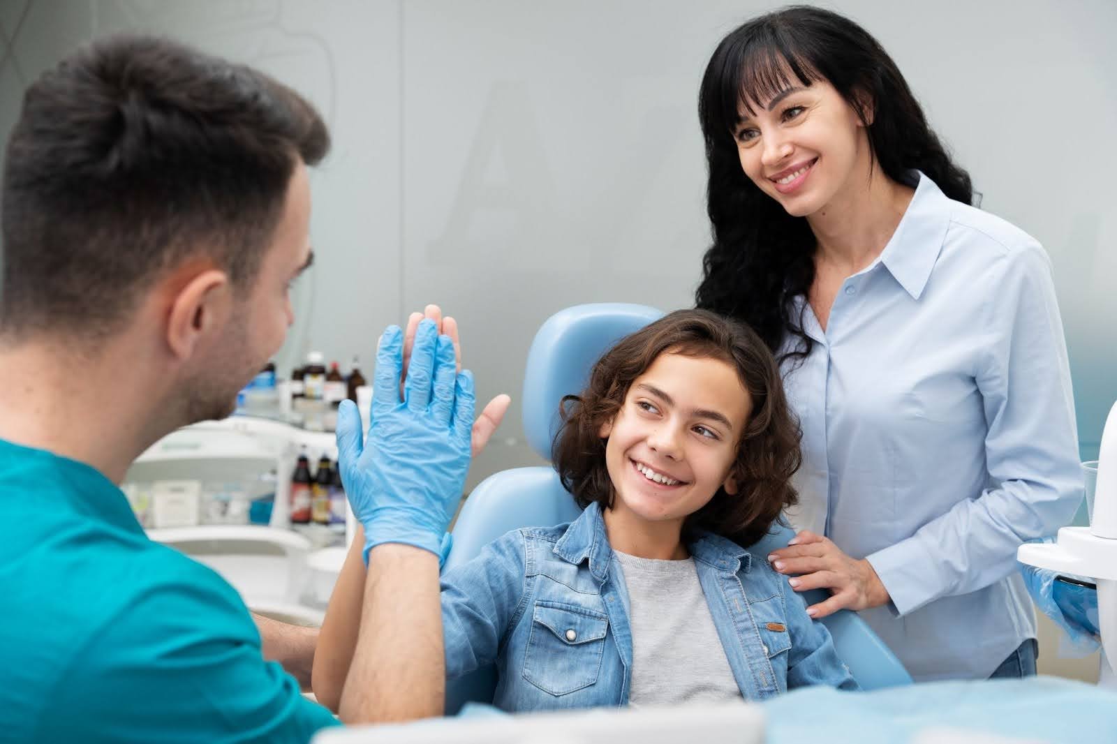 A young patient high-fiving the orthodontist while a parent looks on